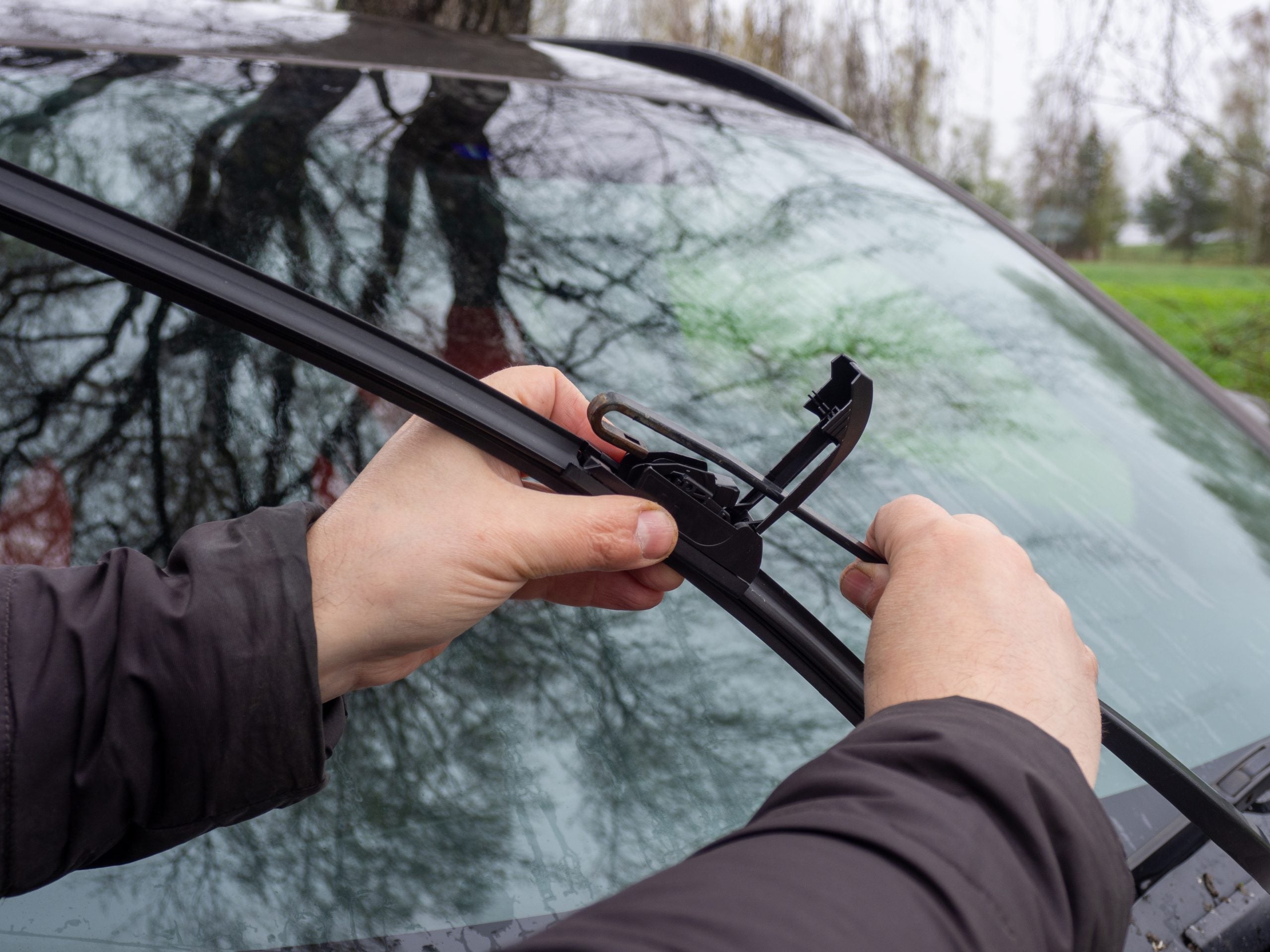 Person replacing windshield wiper blades.