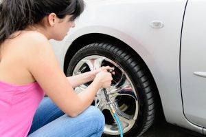 Young women checking her vehicle's tire pressure