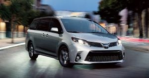 A silver 2020 Toyota Sienna parked in a street at night.