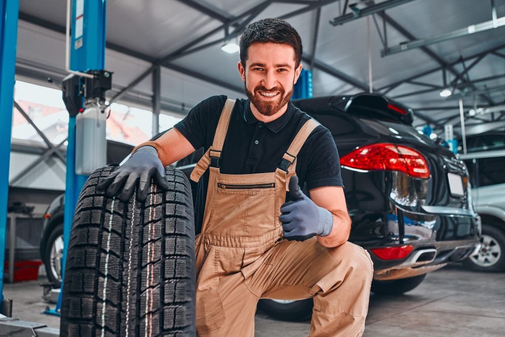 Service technician holding a tire with a smile and thumbs up