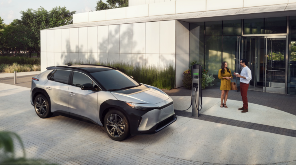 Two people conversing next to a Toyota bZ4X while it charges