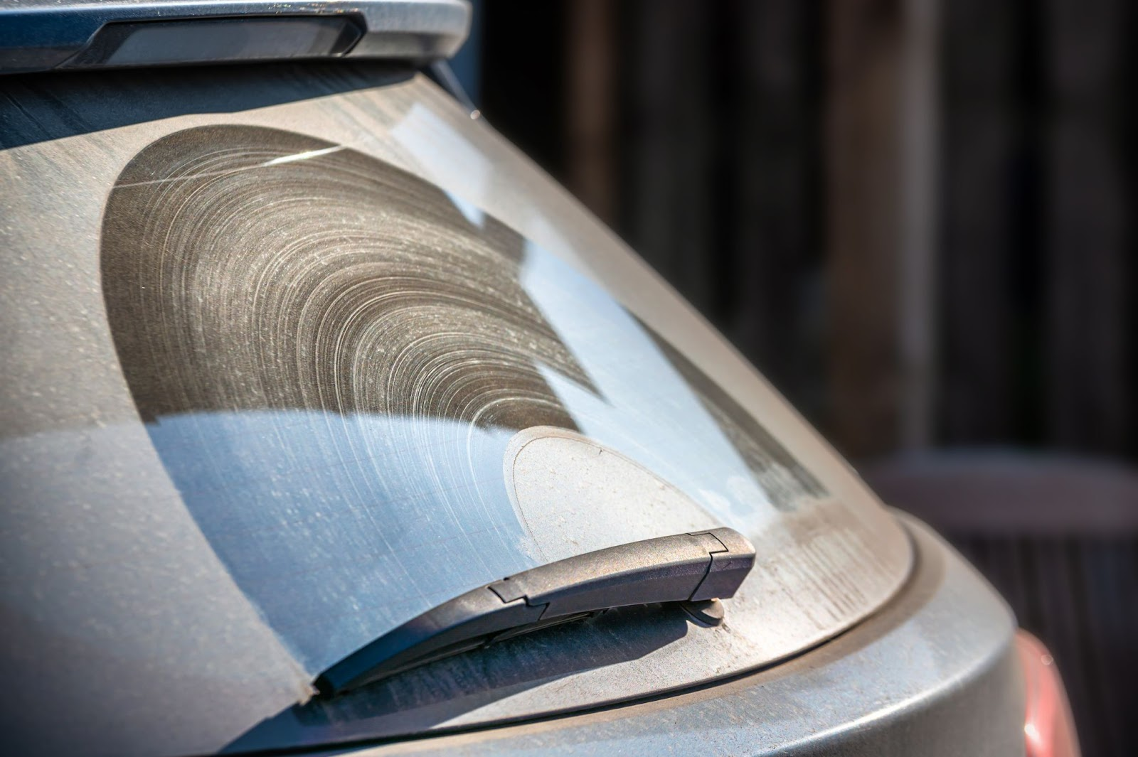 A wiper blade leaving streaks on a dust-covered rear windshield