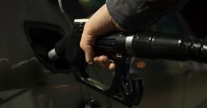 A hand fueling a car with gasoline.