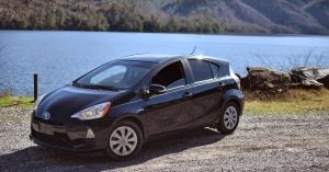 A black Prius C parked by the edge of a lake in the Tennessee mountains.