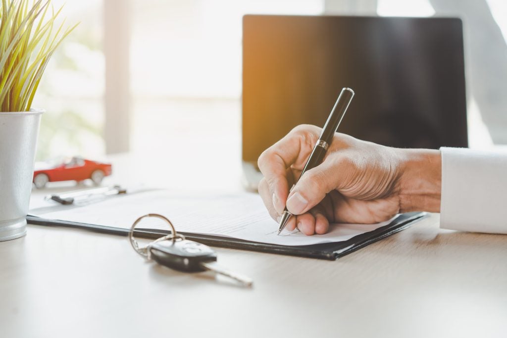  A person signing paperwork next to a car key