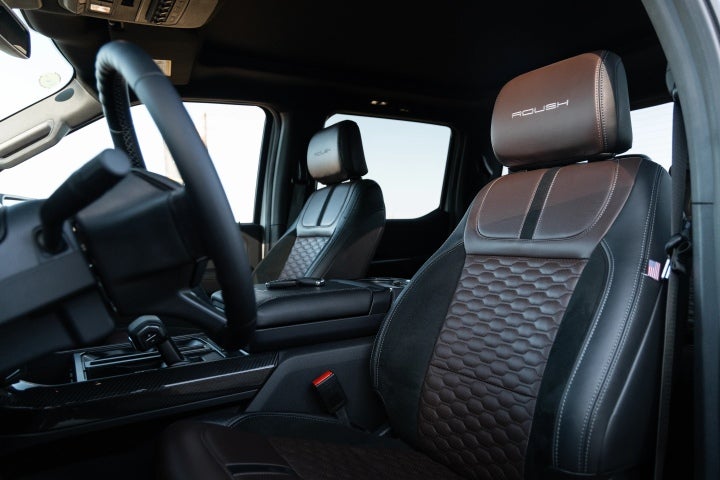 Close-up of black and brown leather front seats with ROUSH branding inside a Ford F-150 pickup.
