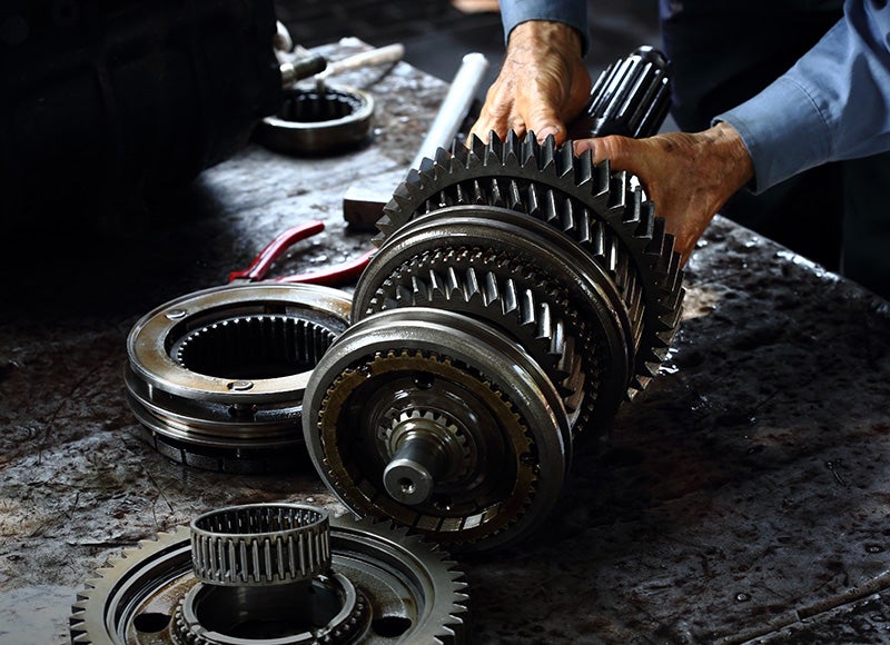 Mechanic assembling metal transmission gears on a workbench.