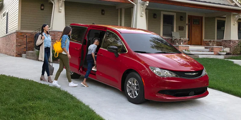 A family getting into their 2025 Chrysler Voyager in a driveway near Highland Park, MI