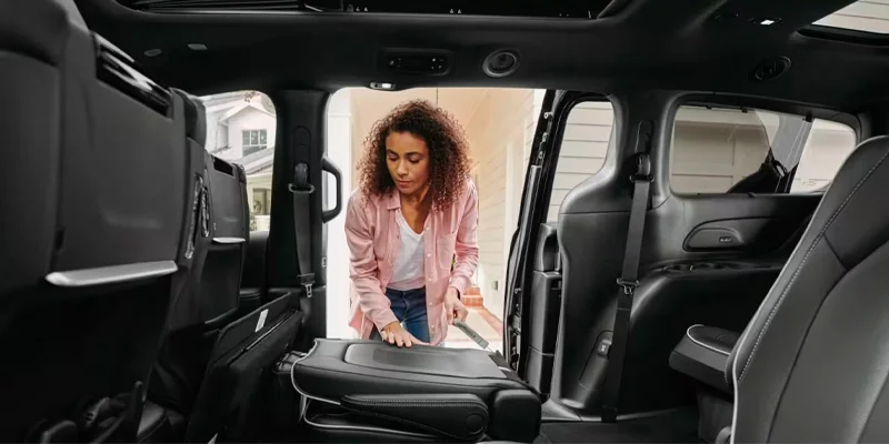 A person inspeciting the interior of their 2025 Chysler Pacifica Plug-in Hybrid in their driveway near Highland Park, MI