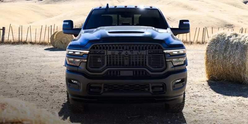 Black RAM heavy-duty pickup on a rural dirt road.