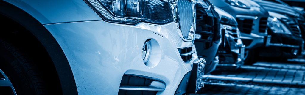 Close-up of parked cars lined up in a dealership lot.