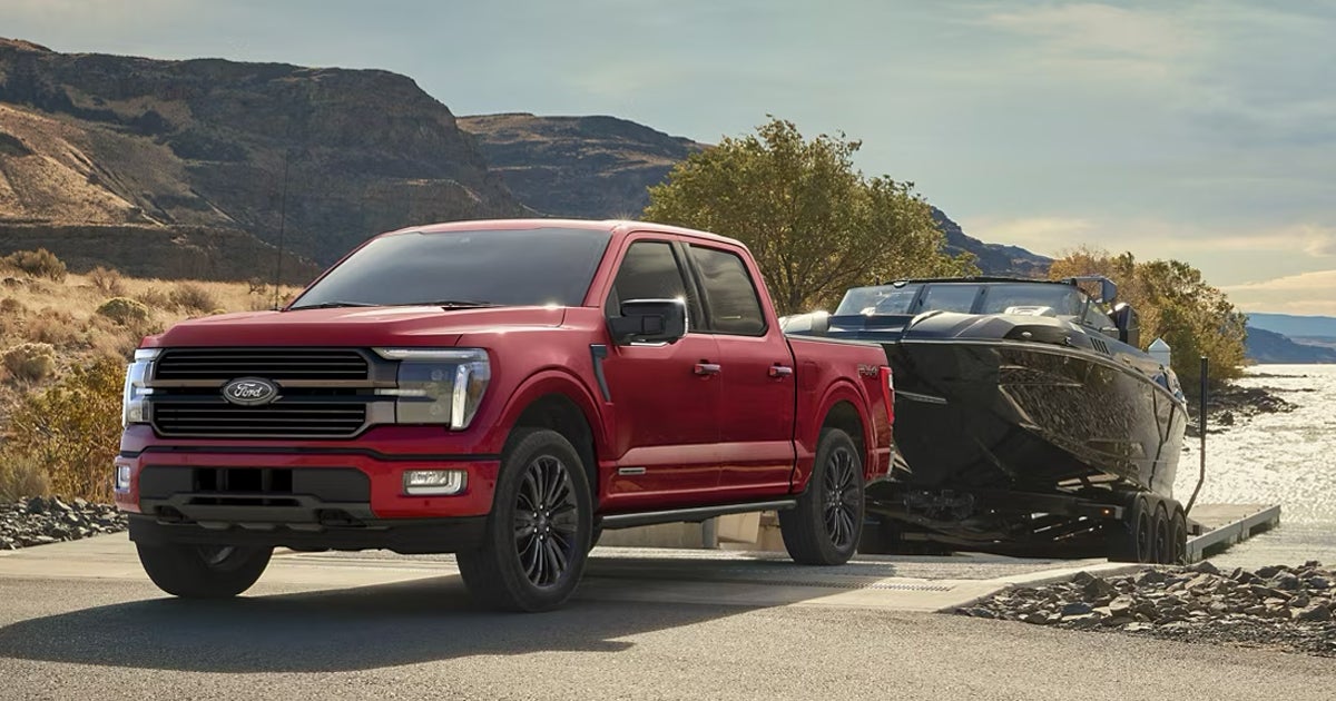 A red Ford F-150 pickup truck towing a boat behind it.