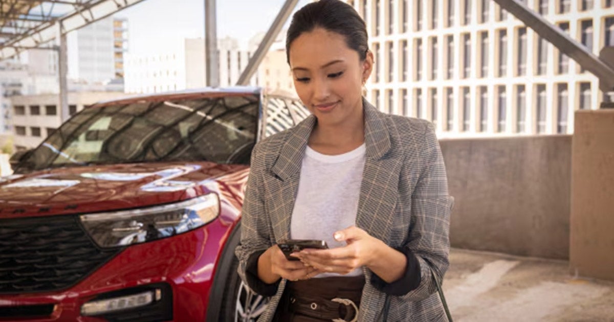 Woman checking her phone for Ford vehicles and services.