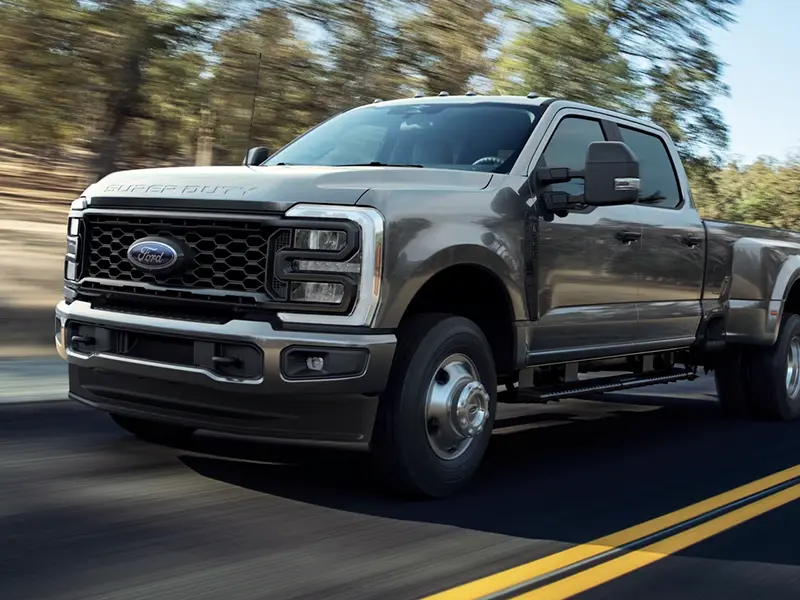 A Ford Super Duty truck driving on a road with trees in the background