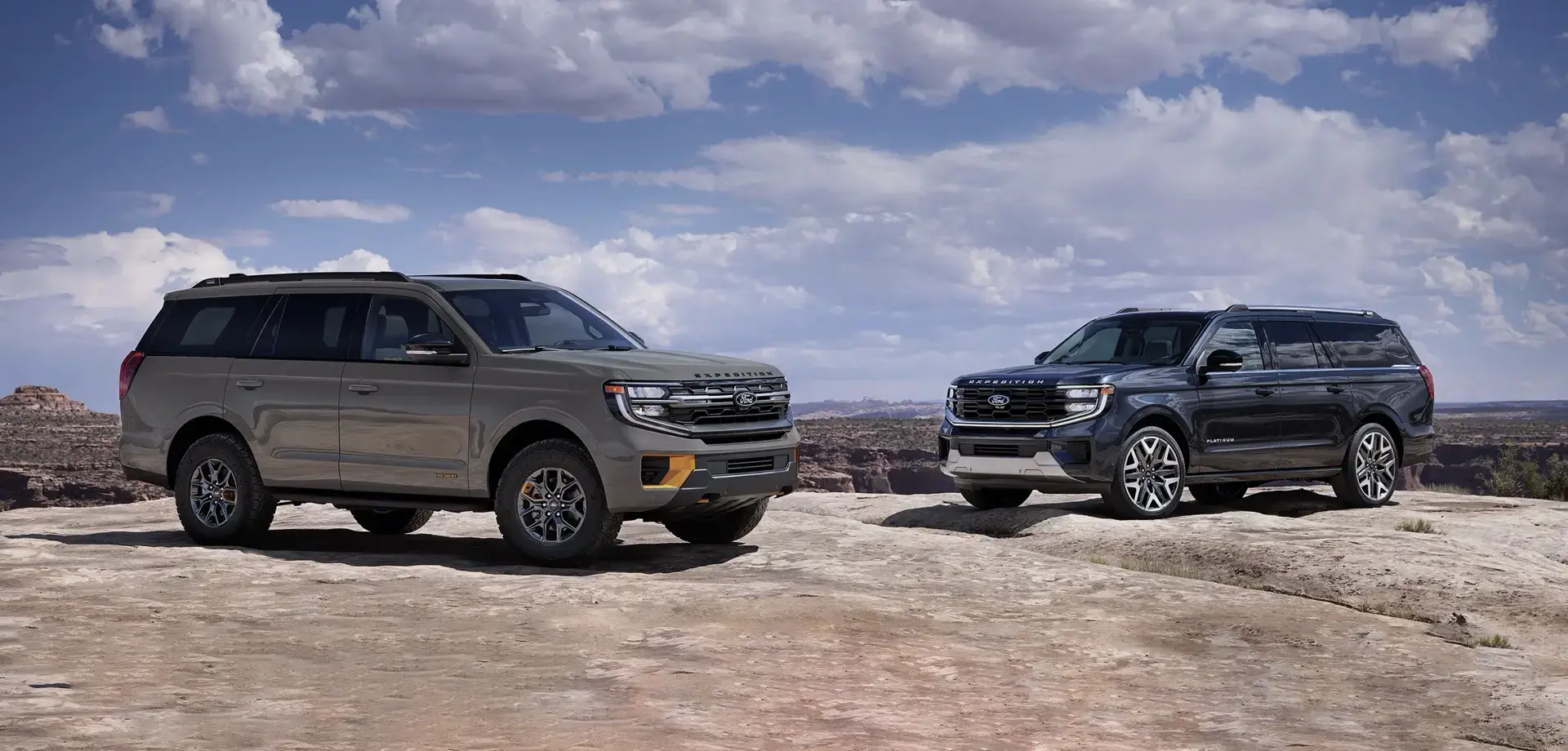 Two Ford Expedition SUVs parked on rocky terrain, showcasing the different models with a mountainous landscape and clear skies in the background