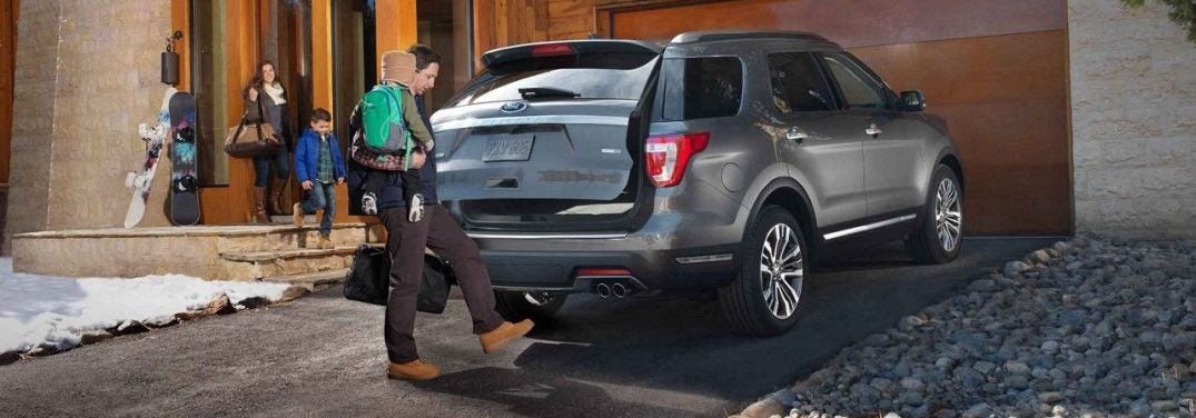 Man holding a child opening the trunk of a 2018 Ford Explorer using his foot