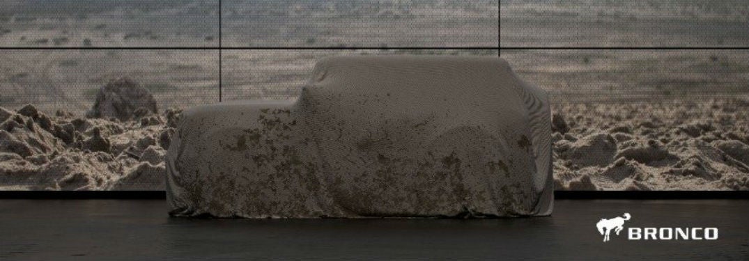 2020 Ford Bronco concealed under sheet with rocky background and bronco logo
