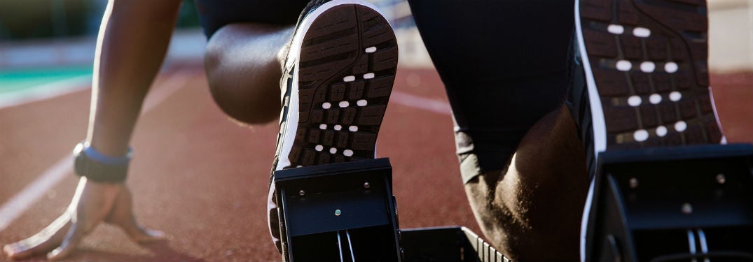 back view of runners shoes on stand crouching on track