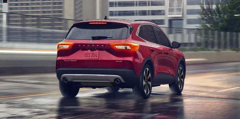 A red 2025 Ford Escape driving down a road in the rain.