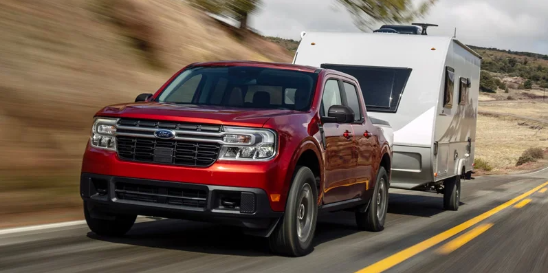 a red 2025 Ford Maverick towing a camper down the road.