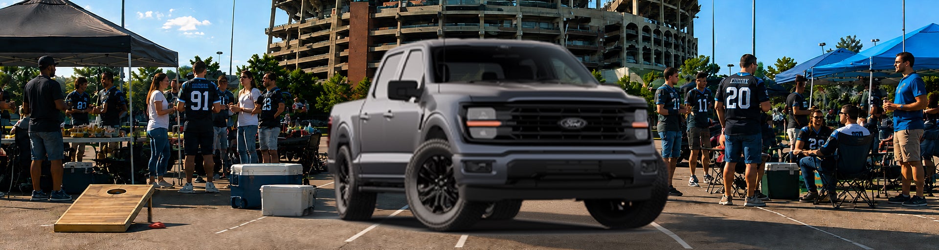A gray Ford F-150 pickup truck parked at a tailgate event outside a stadium.