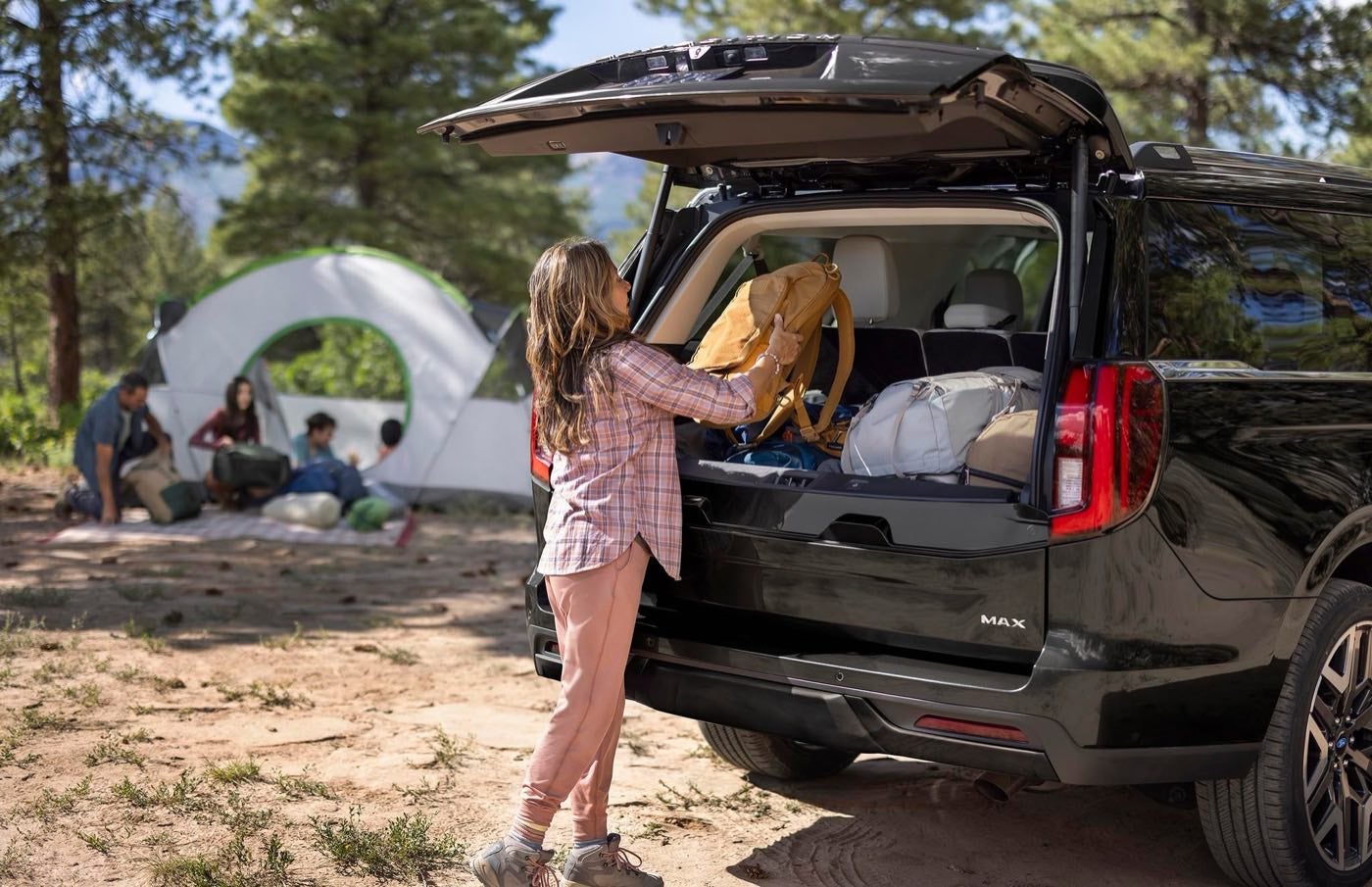 Person loading camping gear through the open split gate of a Ford Expedition