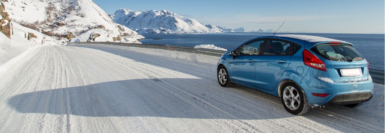 Blue car driving down snow-covered highway