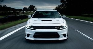 white dodge charger driving on a road while cloudy