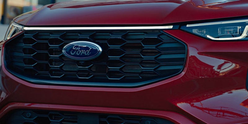 Close-up of a red Ford vehicle's front grille, showcasing the iconic Ford logo in the center.