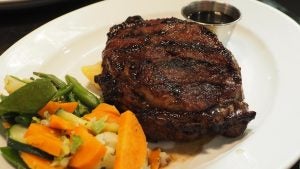 Grilled steak and mixed vegetables on a white dinner plate.