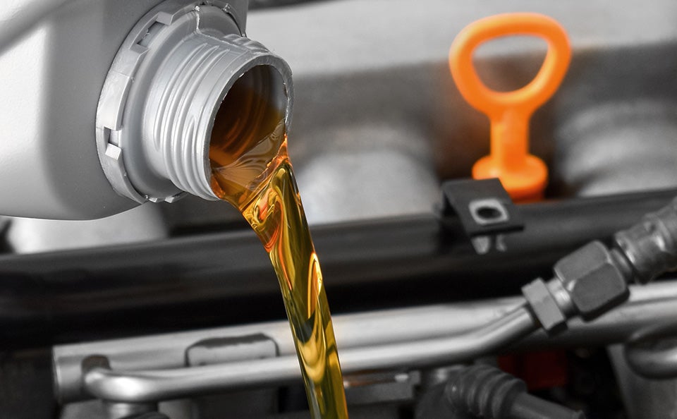 Pouring golden motor oil into an engine bay.