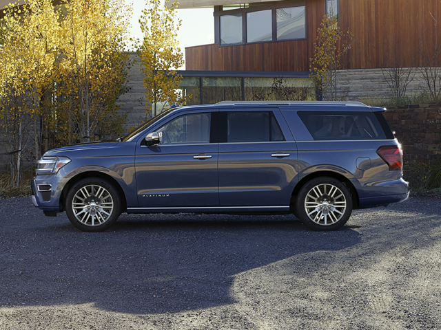 A Ford Expedition Max parked next to a building and some trees