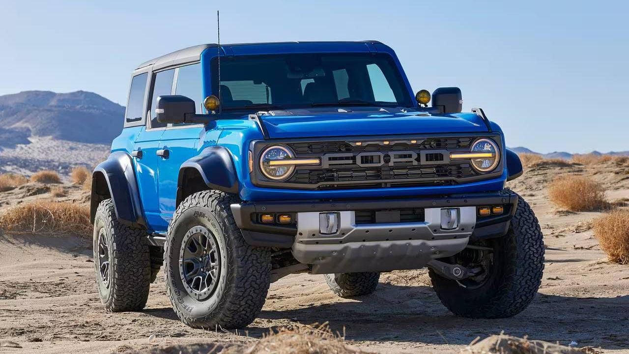 Blue 2025 Ford Bronco driving over sand in a plane