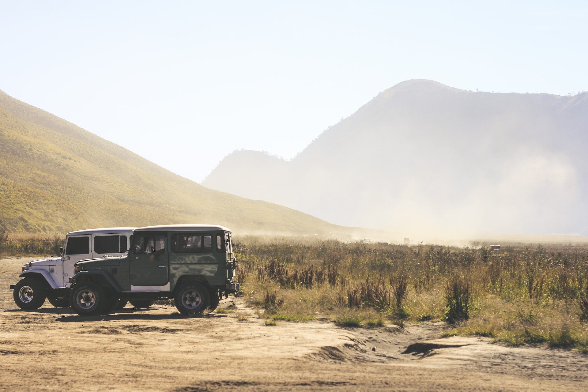two gray and green Jeep Wranglers on grass field