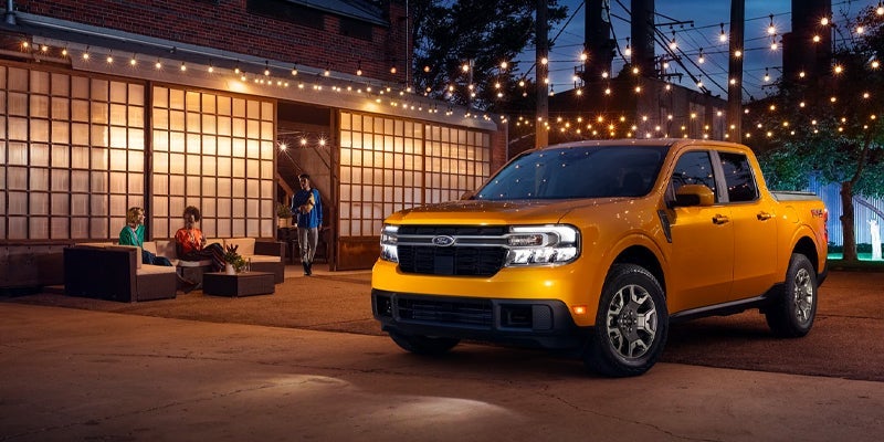 Orange 2023 Ford maverick parked in driveway under string lights