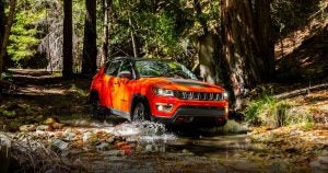A red 2019 Jeep Compass driving through a shallow creek near Wichita, KS