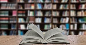 An open book sitting on a table with bookshelves in the background at a local bookstore in Wichita,KS