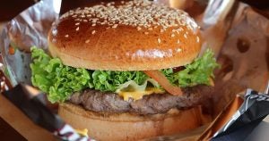 A cheeseburger with lettuce and tomato in an aluminum wrapper served at a local fast-food restaurant in Wichita, KS