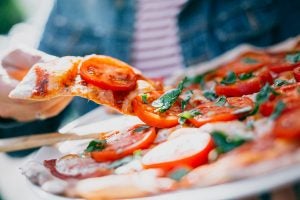 Person Grabbing Slice of Pizza
