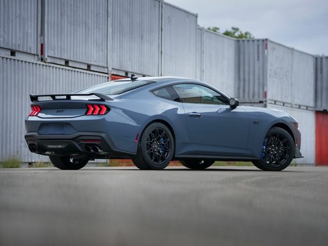 An All-New 2024 Vapor Blue Metallic Ford Mustang GT parked in a shipping container lot in Norwood, MA