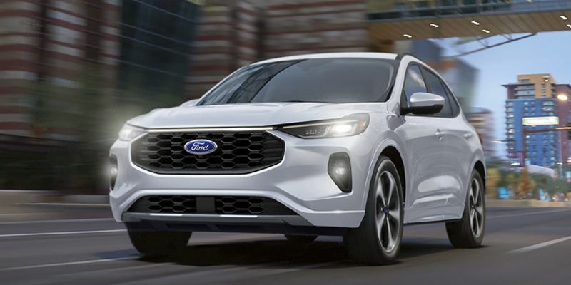 An all-new white 2025 Ford Escape driving through a downtown setting. - Jack Madden Ford