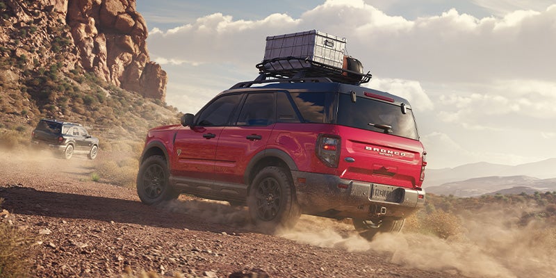 Two, one black and one red, all-new 2025 Ford Bronco Sport's off-roading up a desert mountain. - Jack Madden Ford Norwood, MA