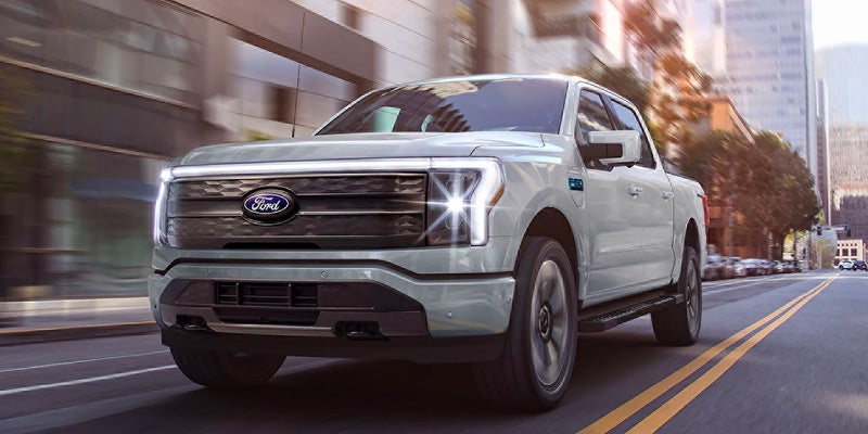 A 2025 Ford F-150 Lightning driving down with its bright headlights in Starke, FL 