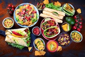 table full of tacos, nachos, salsa ,and avocado 