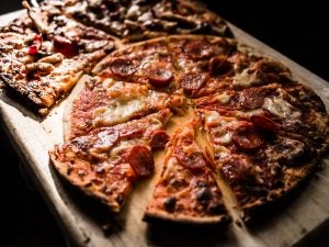 This a sliced pepperoni pizza on a wooden cutting board