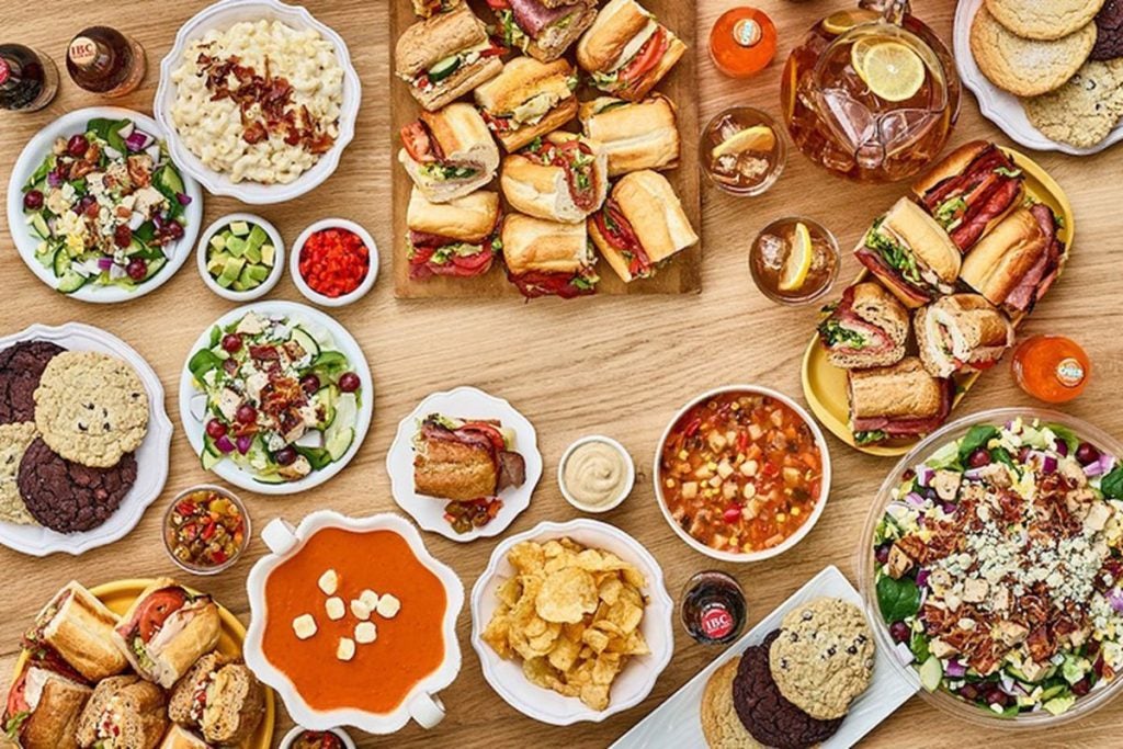 aerial view spread of a variety of sandwiches, salads, dips, and cookies.