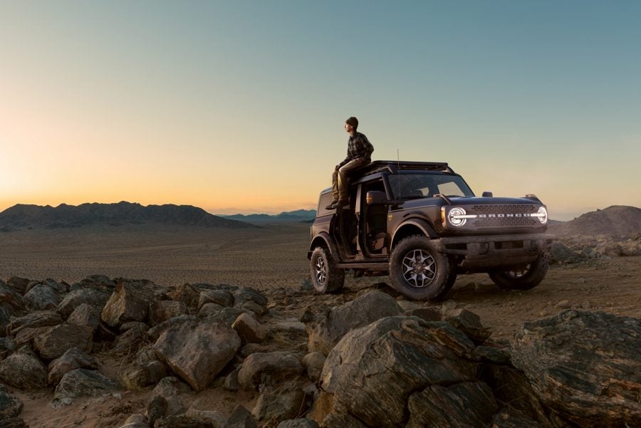Bronco sport in the mountains with person leaning against it