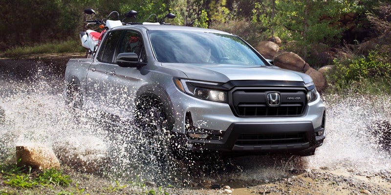 Silver pickup truck driving through a shallow stream.