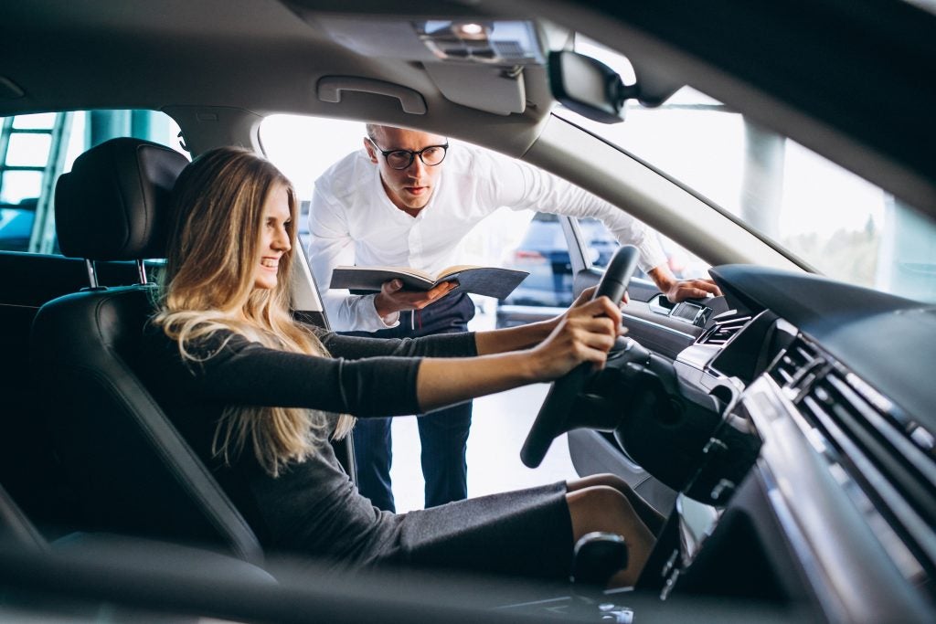 Young,Woman,Testing,A,Car,From,A,Car,Showroom