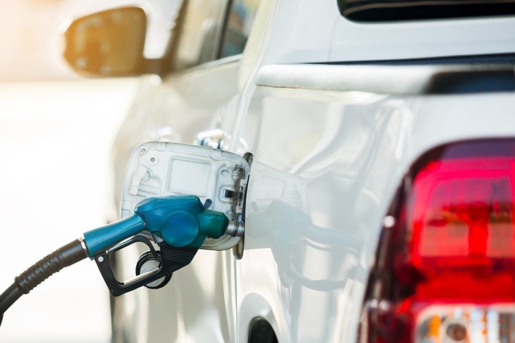 Hand refilling the white pickup truck with fuel at the gas station. Oil and gas energy.